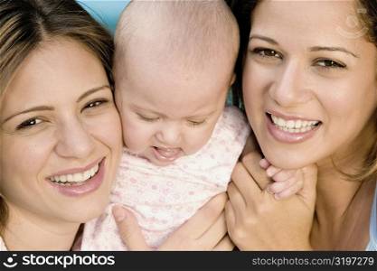 Close-up of two young women holding a baby girl