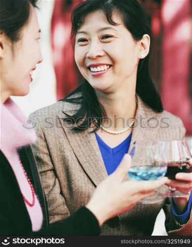Close-up of two young women holding glasses of alcohol