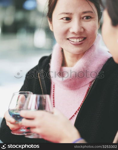 Close-up of two young women holding glasses of alcohol