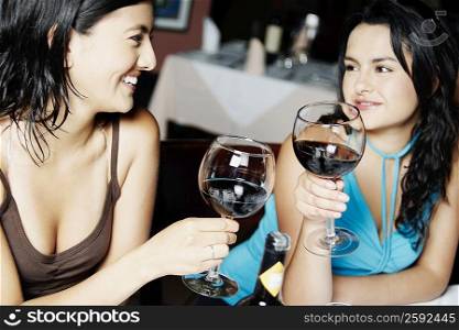 Close-up of two young women holding glasses of wine and smiling
