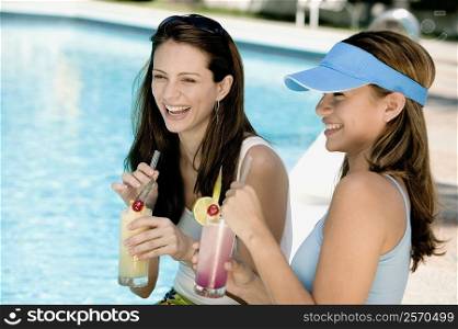 Close-up of two young women holding juice glasses