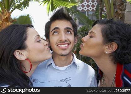 Close-up of two young women kissing a young man