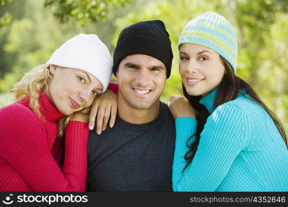 Close-up of two young women leaning on a mid adult man&acute;s shoulders