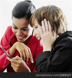 Close-up of two young women looking at a mobile phone and smiling