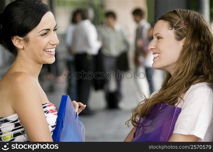 Close-up of two young women looking at each other and smiling