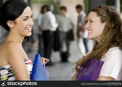 Close-up of two young women looking at each other and smiling