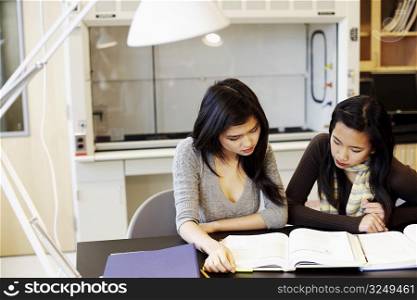 Close-up of two young women sitting at a table and studying
