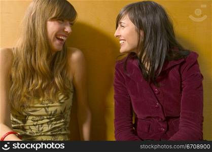 Close-up of two young women smiling and looking at each other