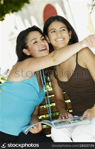 Close-up of two young women smiling and sitting on the bench