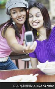 Close-up of two young women taking a photograph of themselves with a mobile phone