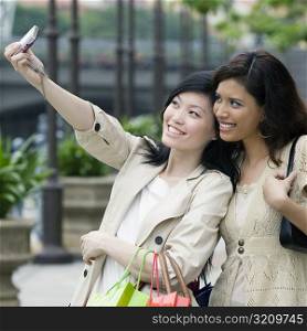 Close-up of two young women taking picture of themselves with a mobile phone
