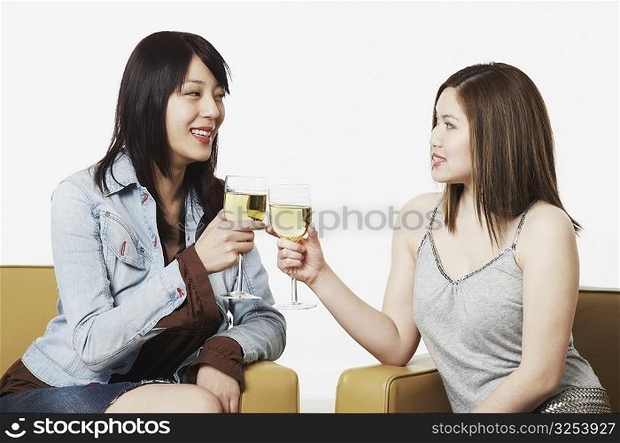 Close-up of two young women toasting with wineglasses