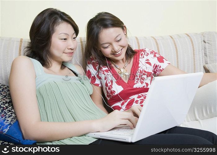 Close-up of two young women using a laptop and smiling