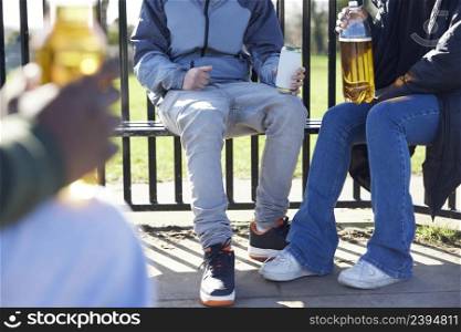 Close Up Of Underage Teenagers Drinking Alcohol In Park