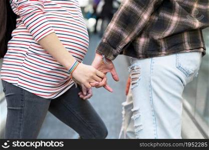 Close up of Unrecognizable Lesbian Pregnant Couple holding hands outdoors. High quality photo. Close up of Unrecognizable Lesbian Pregnant Couple holding hands outdoors.