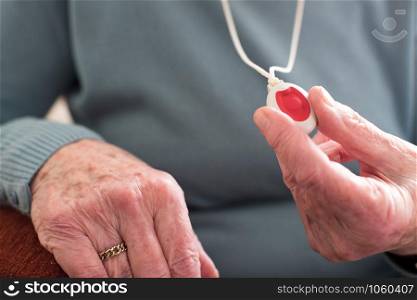 Close Up Of Unwell Senior Woman Holding Personal Alarm Button At Home
