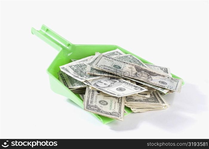 Close-up of US dollar bills in a dustpan
