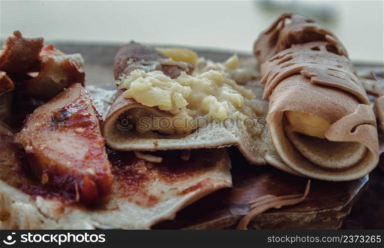 Close-up of Variety of Homemade soft Waffle or Pancake rolls stuffed with vanilla custard or pork, sausage inside placed on a wooden board. Delicious Thai Dessert (kanom To-kyo), Selective focus.