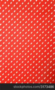 Close-up of vibrant red vintage fabric with repetitive white designs.