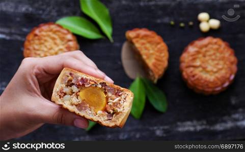 Close up of Vietnamese sweet food from top view, woman hand take moon cake for mid autumn festival when full moon, delicious homemade mooncake of Vietnam cuisine culture