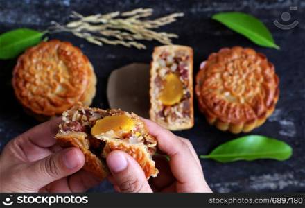 Close up of Vietnamese sweet food from top view, woman hand take moon cake for mid autumn festival when full moon, delicious homemade mooncake of Vietnam cuisine culture