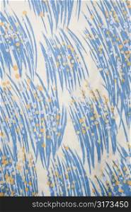 Close-up of vintage fabric with abstract blue and yellow brushstrokes printed on polyester.