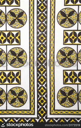 Close-up of vintage fabric with black and yellow shapes and patterns printed on polyester.