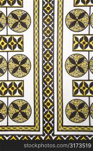 Close-up of vintage fabric with black and yellow shapes and patterns printed on polyester.