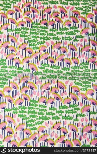 Close-up of vintage fabric with pink flowers and green fish printed on polyester.