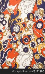 Close-up of vintage fabric with red blue and gold flowers and swirls printed on polyester.