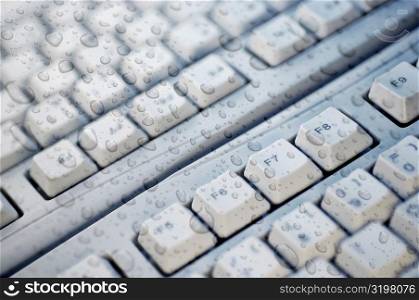 Close-up of water drops on glass over a computer keyboard