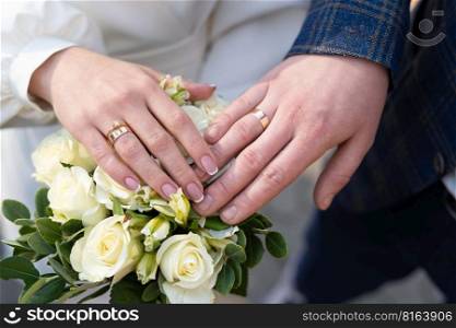 close-up of wedding rings on the hands of the bride and groom, a couple in love holding hands together