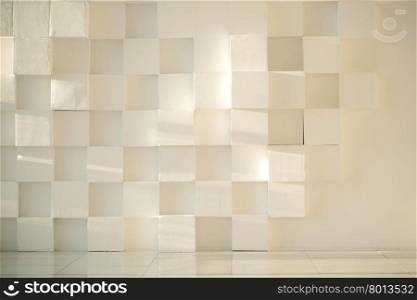 Close-up of white painted concrete modern wall made of cubes with tiled floor. White painted concrete wall made of cubes with tiled floor