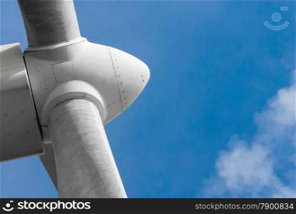 Close-up of white propeller head on wind turbine against blue sky and cloud.