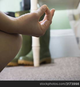 Close up of woman&acute;s hand resting on her knee with fingers in meditation pose.