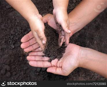 Close up of Woman and her child holding soil in hands. Environmental concept.