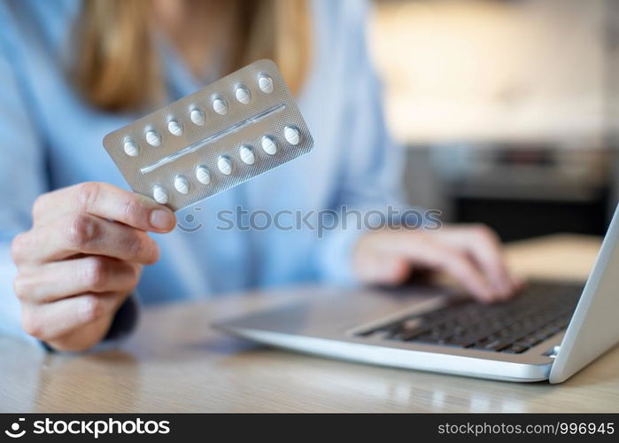 Close Up Of Woman At Home Looking Up Information About Medication Online Using Laptop