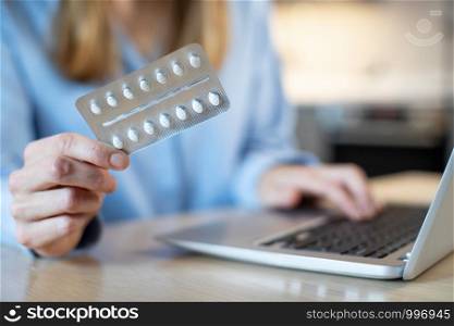 Close Up Of Woman At Home Looking Up Information About Medication Online Using Laptop