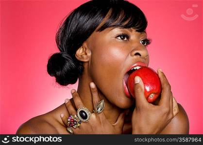 Close up of woman biting an apple over colored background