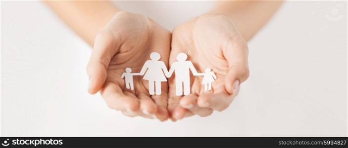 close up of woman cupped hands showing paper man family. woman hands with paper man family