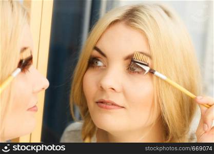Close up of woman doing her make up, preparing lashes using brush tool brushing eyelashes.. Woman brushing her eyelashes