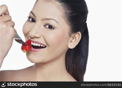 Close-up of woman eating strawberry over white background