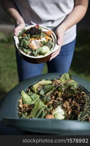 Close Up Of Woman Emptying Food Waste Into Garden Composter At Home