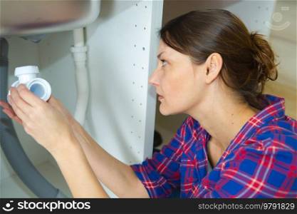 close-up of woman fixing sink pipe with wrench