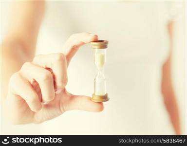 close up of woman hand holding hourglass.