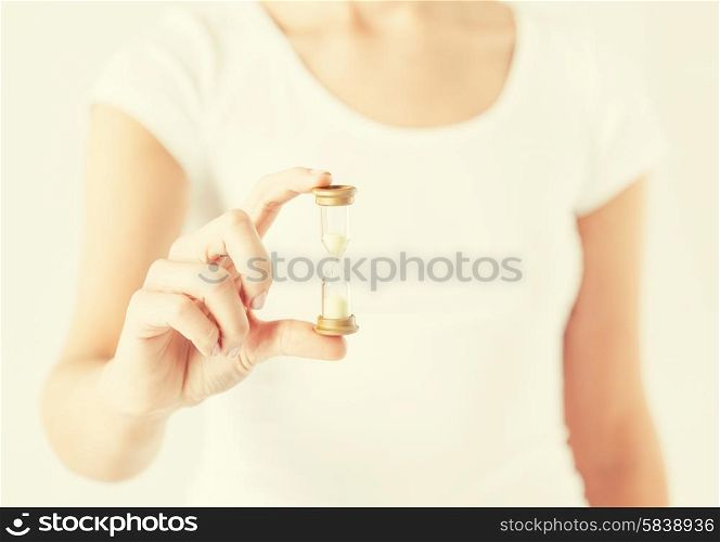 close up of woman hand holding hourglass.