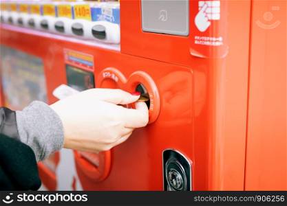 Close up of woman hand inserting coin in vending machine.