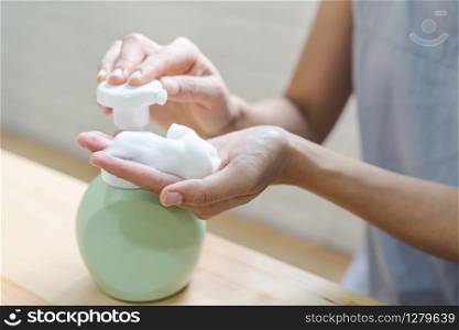 Close up of woman hand take cleaner foam from pump foam cleanser bottle. Close up of woman hand take cleaner foam