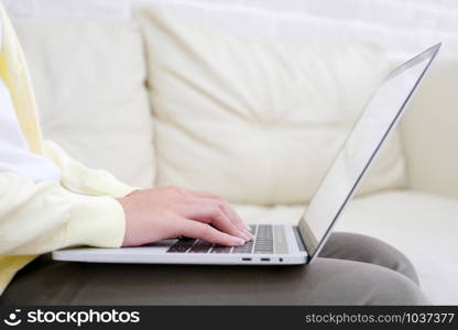 Close up of woman hand using laptop computer iwhile sitting on sofa in casual lifestyle, people and technology, lifestyles, working at home