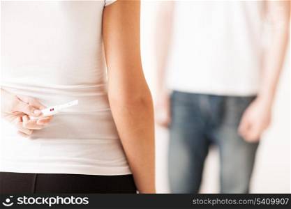 close up of woman hands hiding pregnancy test from man